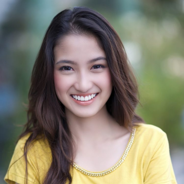 A woman business professional wearing a yellow top and watch takes portrait